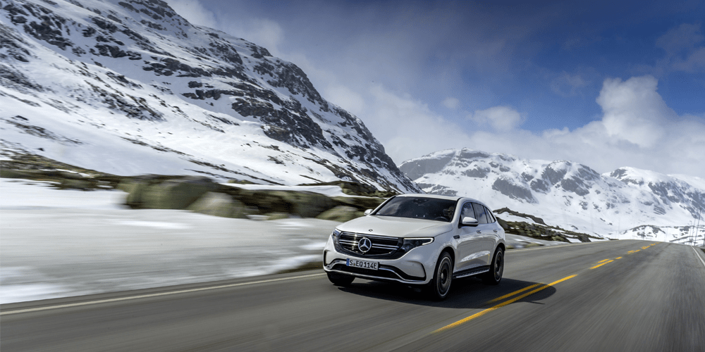 Mercedes EQC circulant sur une route au milieu de montagnes enneigées