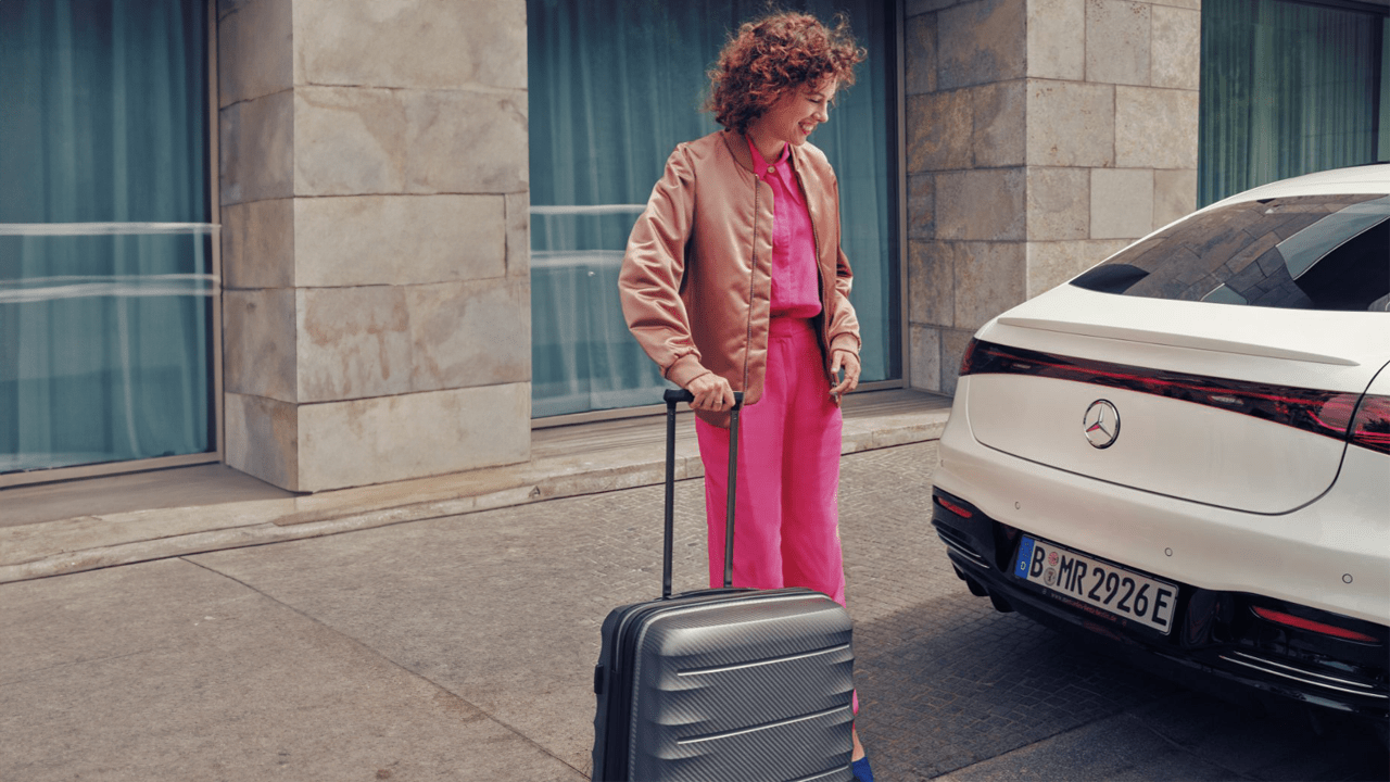 Femme s'apprêtant à ranger sa valise dans le coffre de sa Mercedes