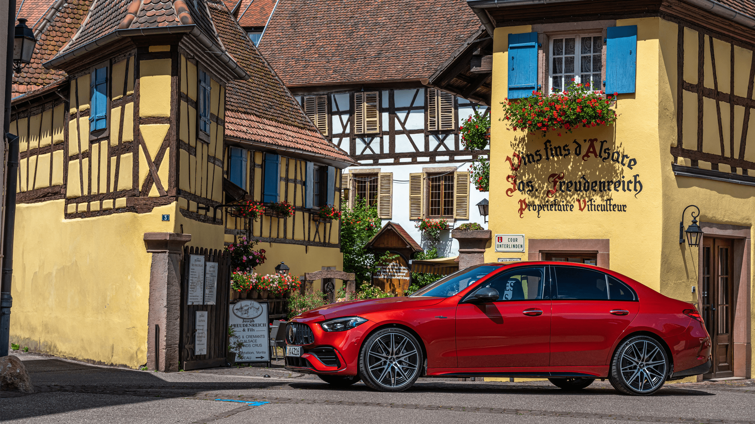 Mercedes avec finition rouge devant une maison à colombages