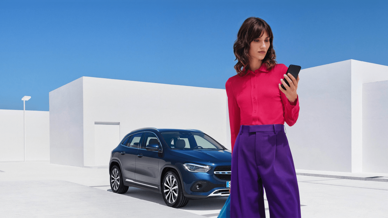 femme sur son smartphone après avoir stationné son véhicule Mercedes