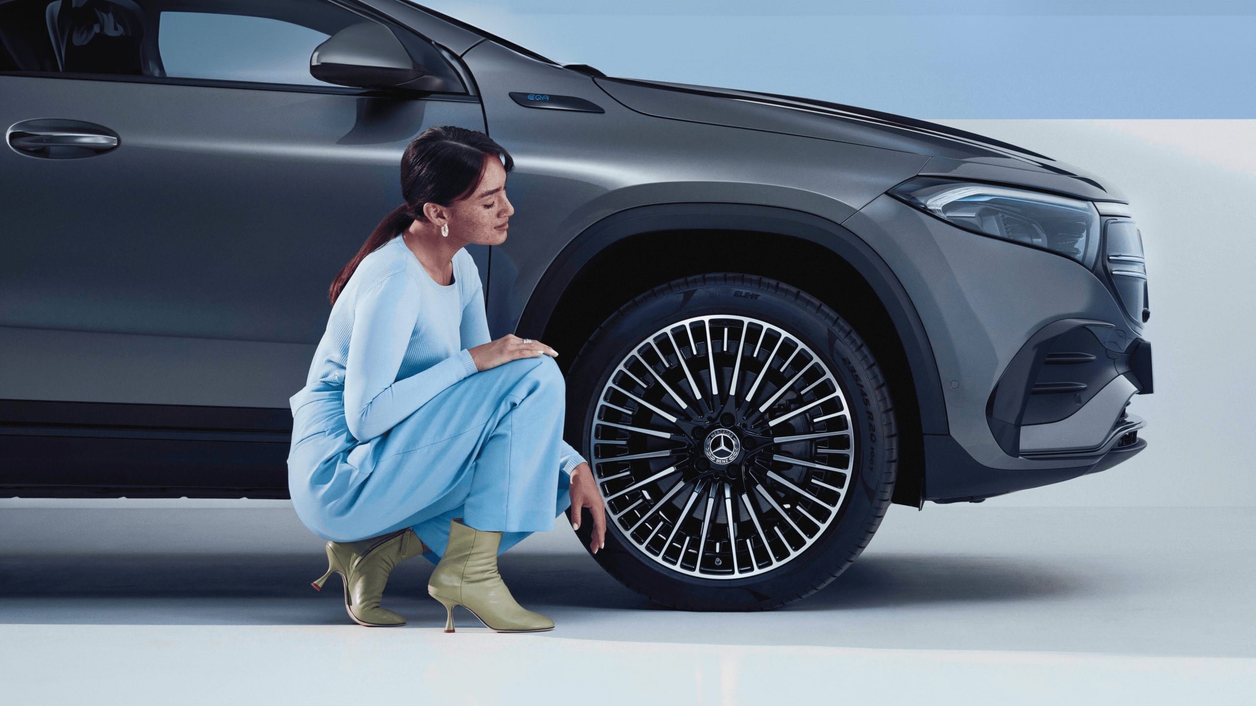 Femme devant le pneu de sa mercedes EQA